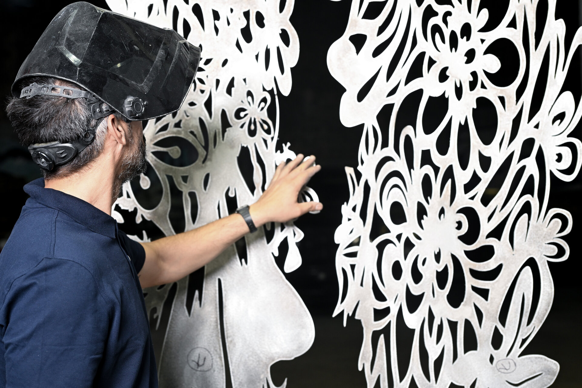 Karel Frometa inspecting custom metalwork panel at Thor Metal Art workshop